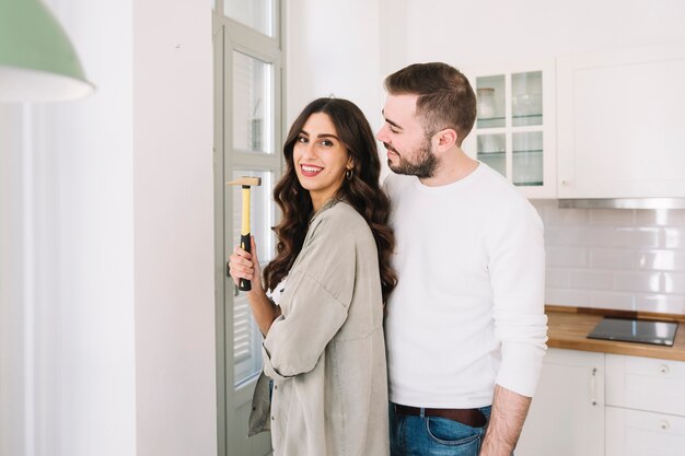 Pareja alegre con martillo en la pared