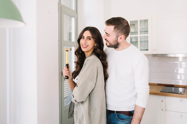 Pareja alegre con martillo en la pared