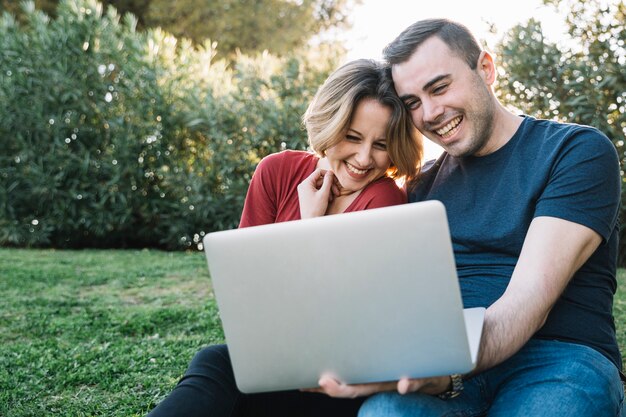 Pareja alegre navegación de la computadora portátil en el suelo