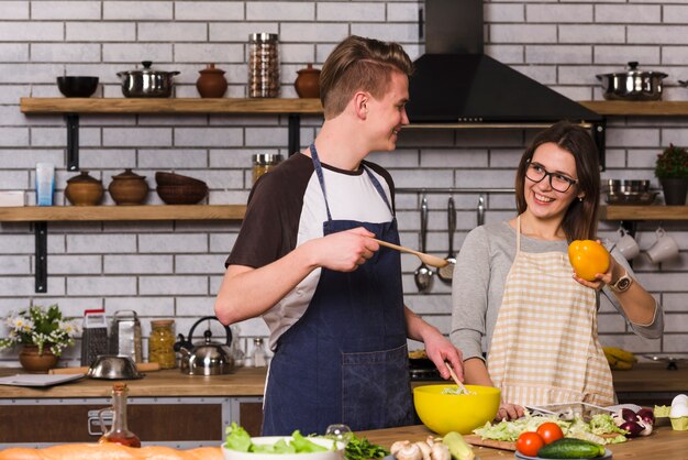 Pareja alegre durante la preparación de la ensalada