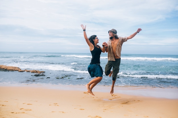 Pareja alegre saltando en la orilla del mar