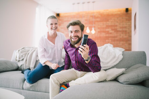 Pareja alegre sentado con control remoto