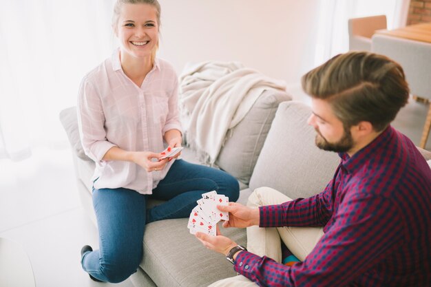 Pareja alegre sentado y jugando a las cartas