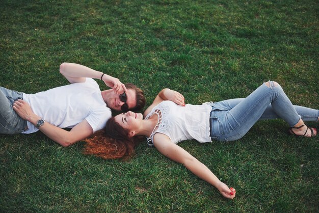 Pareja alegre tirado en el pasto.