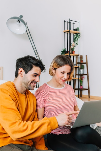 Foto gratuita pareja alegre usando la computadora portátil en el piso