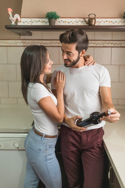 Pareja alegre con vino en la cocina