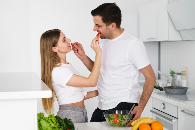 Pareja alimentándose mientras cocina