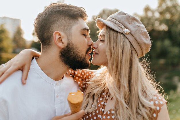 Pareja de amantes besos con los ojos cerrados. Chico y chica en ropa de verano con helado.