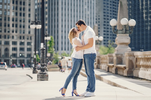 pareja de amantes jóvenes y con estilo en camisetas blancas y jeans caminando en una gran ciudad