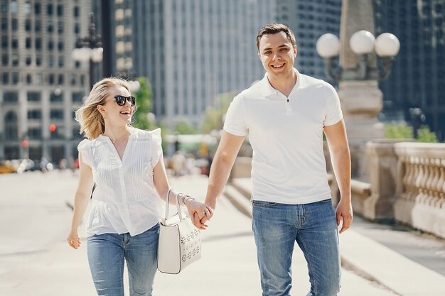 pareja de amantes jóvenes y con estilo en camisetas blancas y jeans caminando en una gran ciudad