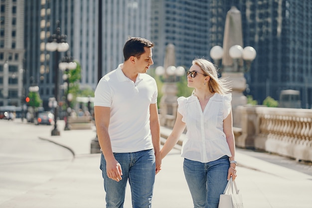 Foto gratuita pareja de amantes jóvenes y con estilo en camisetas blancas y jeans caminando en una gran ciudad