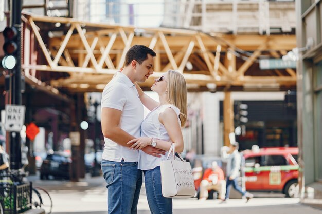 pareja de amantes jóvenes y con estilo en camisetas blancas y jeans caminando en una gran ciudad