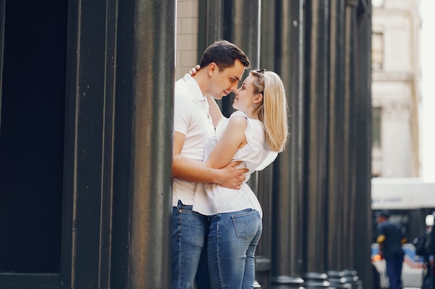 pareja de amantes jóvenes y con estilo en camisetas blancas y jeans caminando en una gran ciudad