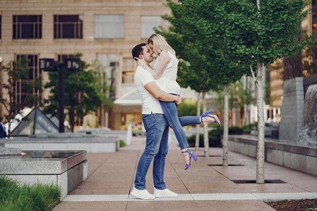 pareja de amantes jóvenes y con estilo en camisetas blancas y jeans caminando en una gran ciudad