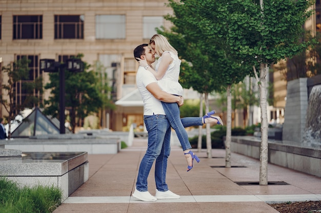 pareja de amantes jóvenes y con estilo en camisetas blancas y jeans caminando en una gran ciudad