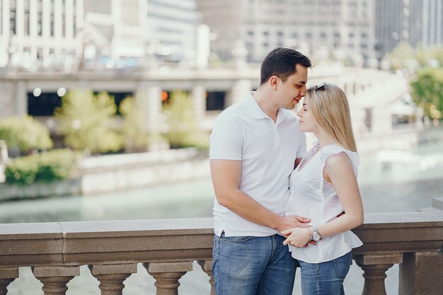 pareja de amantes jóvenes y con estilo en camisetas blancas y jeans de pie en una gran ciudad
