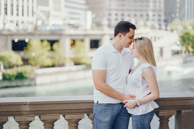 pareja de amantes jóvenes y con estilo en camisetas blancas y jeans de pie en una gran ciudad