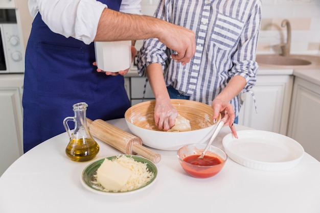 Foto gratuita pareja amasando masa para pizza en un tazón