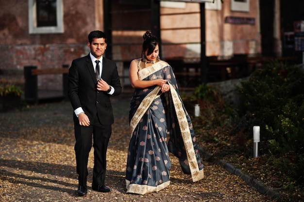 Pareja de amigos indios elegantes y de moda de mujer en sari y hombre en traje