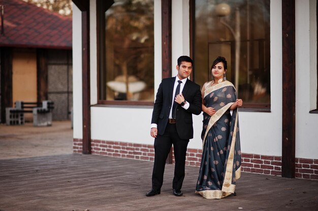 Pareja de amigos indios elegantes y de moda de mujer en sari y hombre en traje