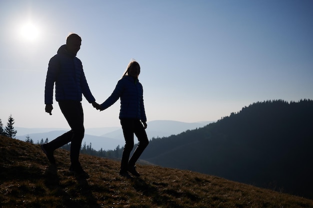 Pareja amorosa cogidos de la mano y caminando por la colina