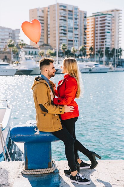 Pareja amorosa con corazón globo en paisaje urbano