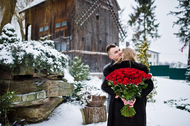 Pareja amorosa enamorada en el día de invierno con un gran ramo de 101 rosas