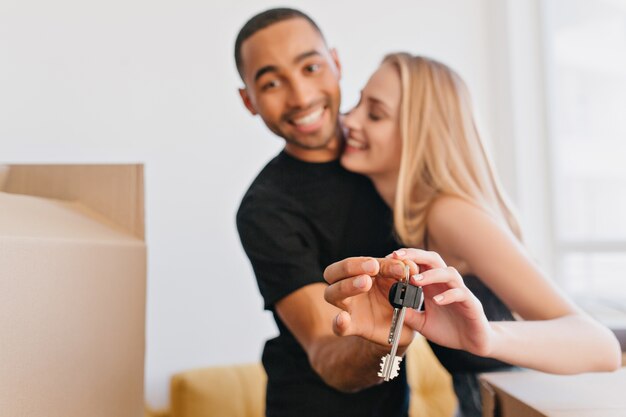 Pareja amorosa mostrando las llaves de la nueva casa, yendo a mudarse a un nuevo apartamento, compró piso, empacando cajas de cartón, mudándose.