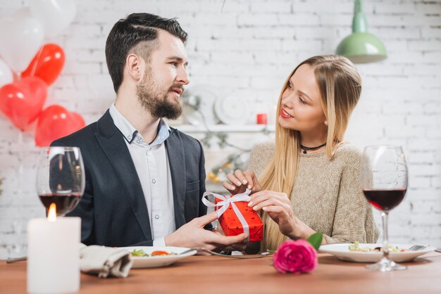 Pareja amorosa con regalo en cena romántica.