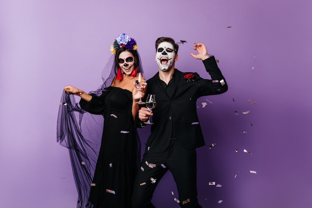 Pareja amorosa en traje de miedo celebrando el día de los muertos. Alegre niña y niño bailando en la fiesta de halloween.