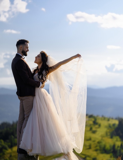 Pareja amorosa en trajes de boda posando en la naturaleza en las montañas