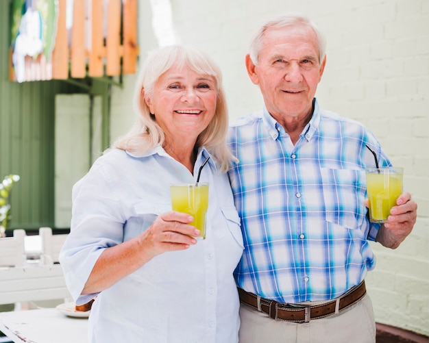 Foto gratuita pareja de ancianos abrazados sosteniendo vasos de jugo