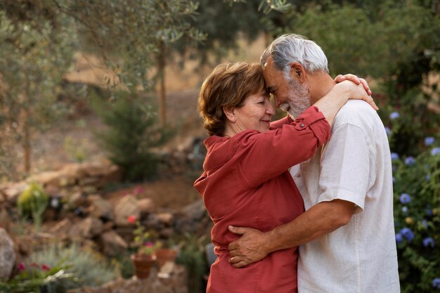 Una pareja de ancianos abrazándose románticamente en el jardín de su casa rural