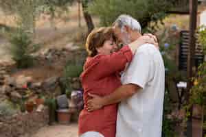 Foto gratuita una pareja de ancianos abrazándose románticamente en el jardín de su casa rural