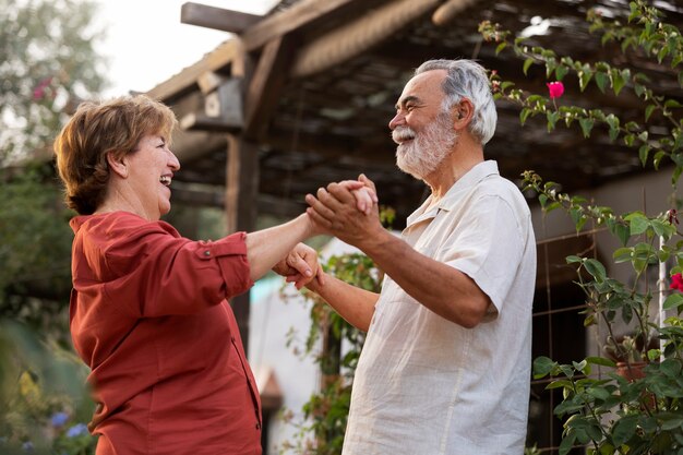 Una pareja de ancianos abrazándose románticamente en el jardín de su casa rural