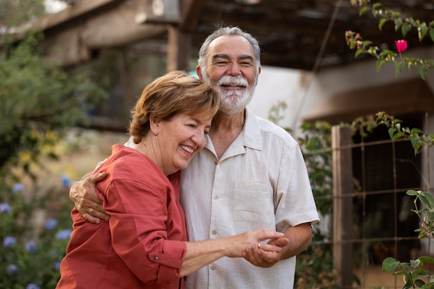 Una pareja de ancianos abrazándose románticamente en el jardín de su casa rural