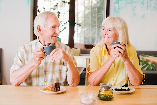 Pareja de ancianos alegre bebiendo té y hablando animadamente