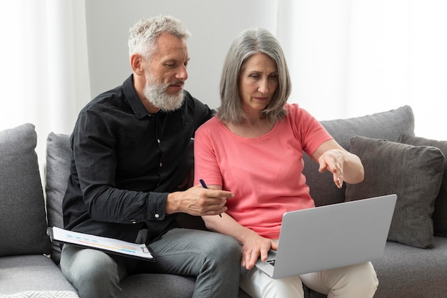 Pareja de ancianos en casa en el sofá con laptop