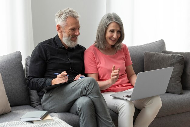 Pareja de ancianos en casa en el sofá con laptop