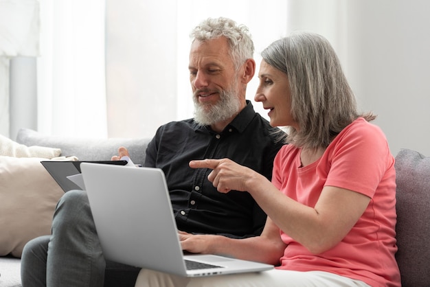 Foto gratuita pareja de ancianos en casa en el sofá con laptop