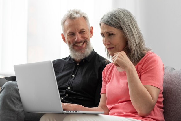 Pareja de ancianos en casa en el sofá con laptop