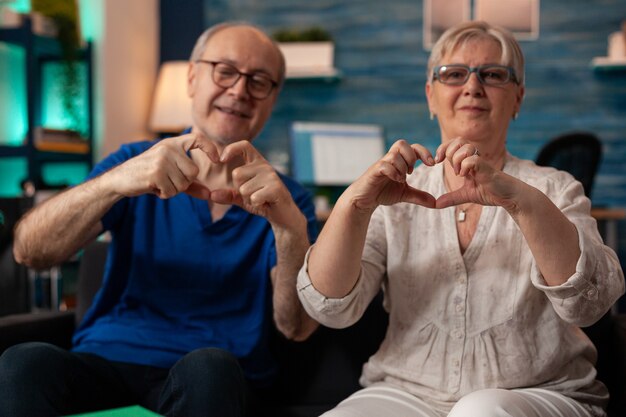 Pareja de ancianos casados haciendo el símbolo del corazón con las manos