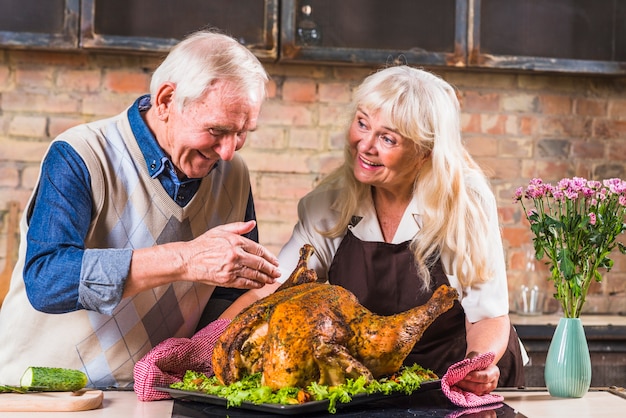 Pareja de ancianos cocinar pavo en la cocina