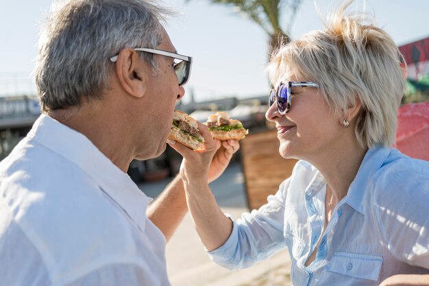 Pareja de ancianos comiendo una hamburguesa al aire libre