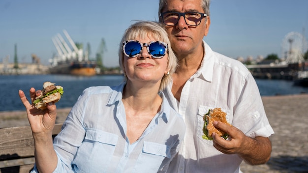 Pareja de ancianos disfrutando de una hamburguesa al aire libre juntos