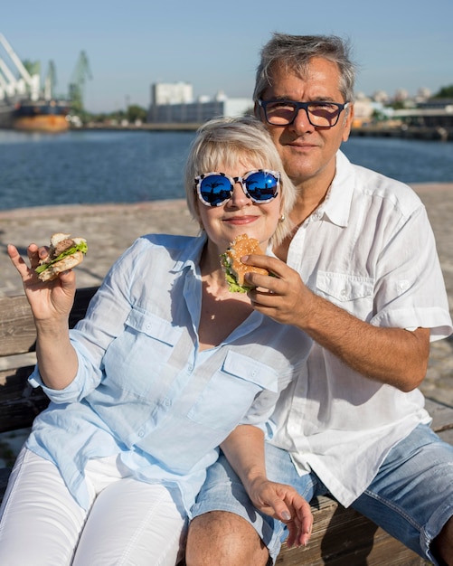 Pareja de ancianos disfrutando de una hamburguesa al aire libre juntos