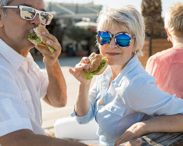 Pareja de ancianos disfrutando de una hamburguesa al aire libre