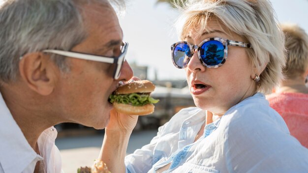 Pareja de ancianos disfrutando de una hamburguesa al aire libre