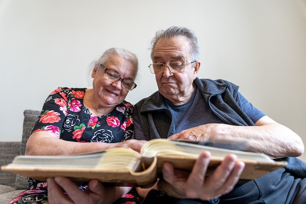 Una pareja de ancianos está mirando fotografías en un álbum de fotos familiar.