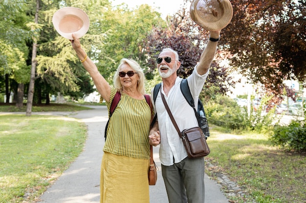 Pareja de ancianos levantando sus sombreros en el aire